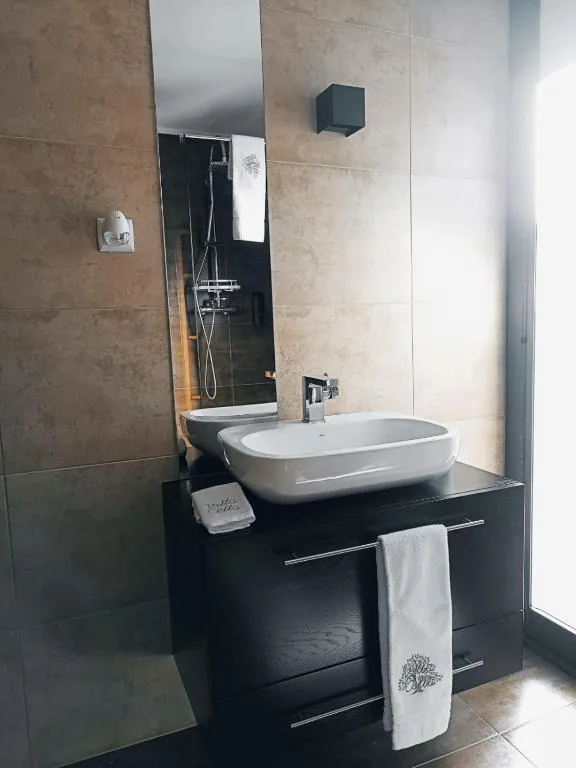 Salle de bain avec vasque sur meuble foncé, miroir et douche